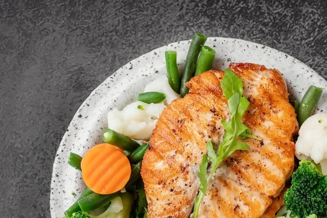 Salmón con verduras al vapor en un plato blanco