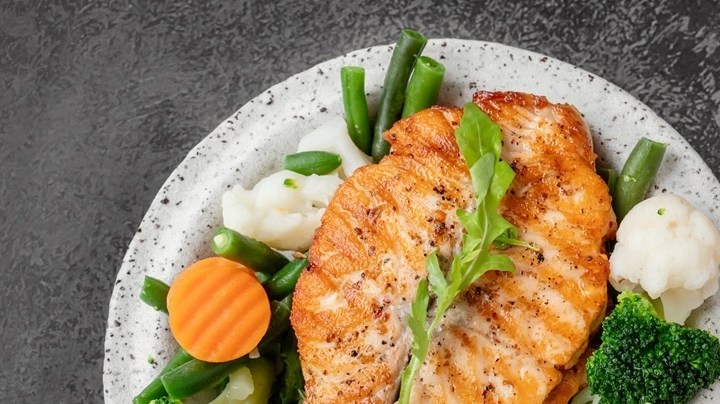 Salmón con verduras al vapor en un plato blanco