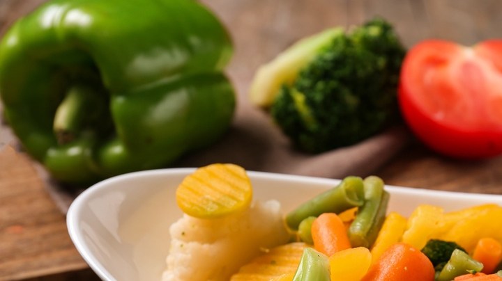 Verduras al vapor sobre un recipiente blanco con una cuchara