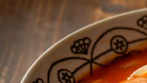 Guiso de fideos con papa y chorizo en un plato hondo sobre una mesa de madera