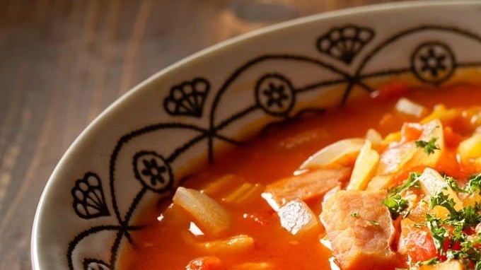 Guiso de fideos con papa y chorizo en un plato hondo sobre una mesa de madera
