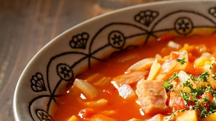 Guiso de fideos con papa y chorizo en un plato hondo sobre una mesa de madera