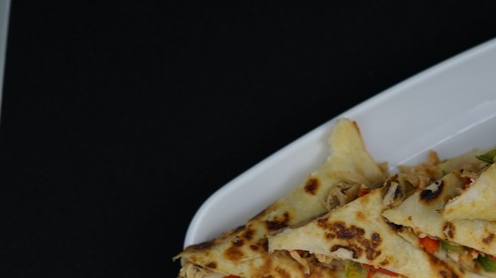 Un plato blanco con quesadillas estilo norteño y unas gotas de salsa