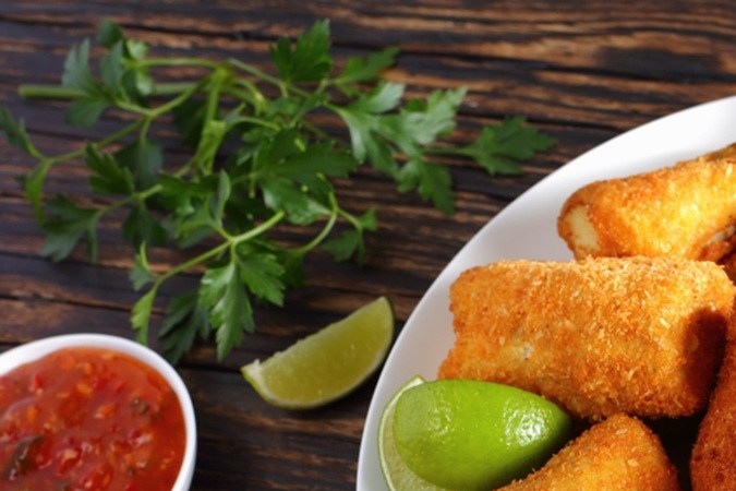 Merluza con costra de pan en un plato blanco